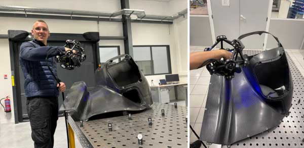 Man in a blue vest using the MetraSCAN to digitize a black front wheel arch on a fixture table equipped with targets.