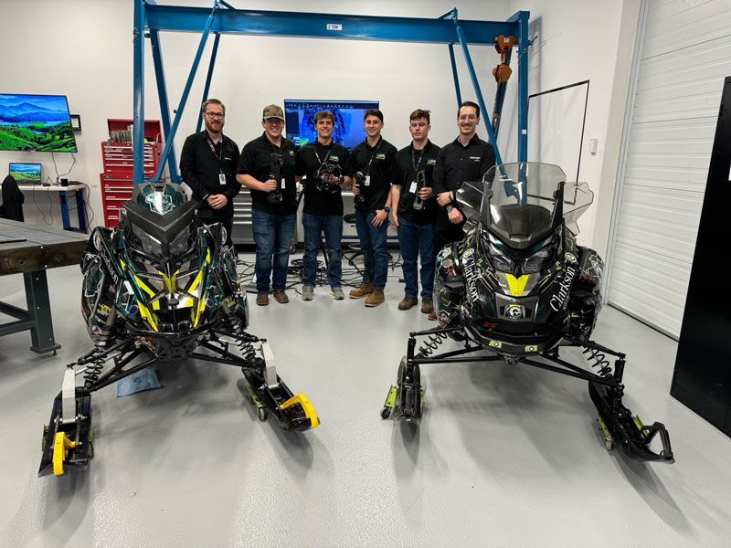 Members of the Clarkson University Clean Snowmobile Team holding Creaform’s 3D scanners behind two snowmobiles.
