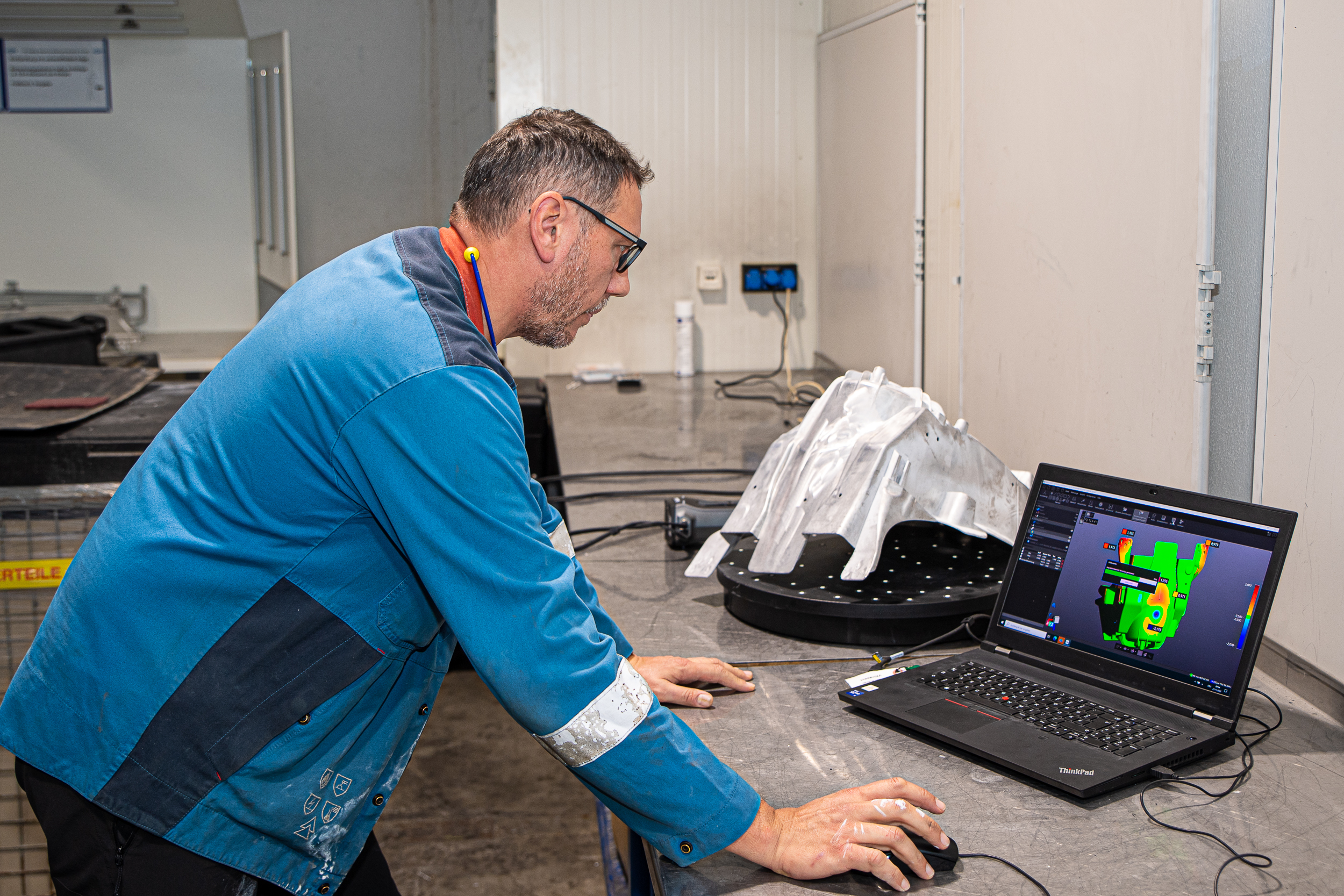 A GF Casting employee looks at the scanned component of the VXinspect software on a laptop. A CAD comparison with colormap can be seen