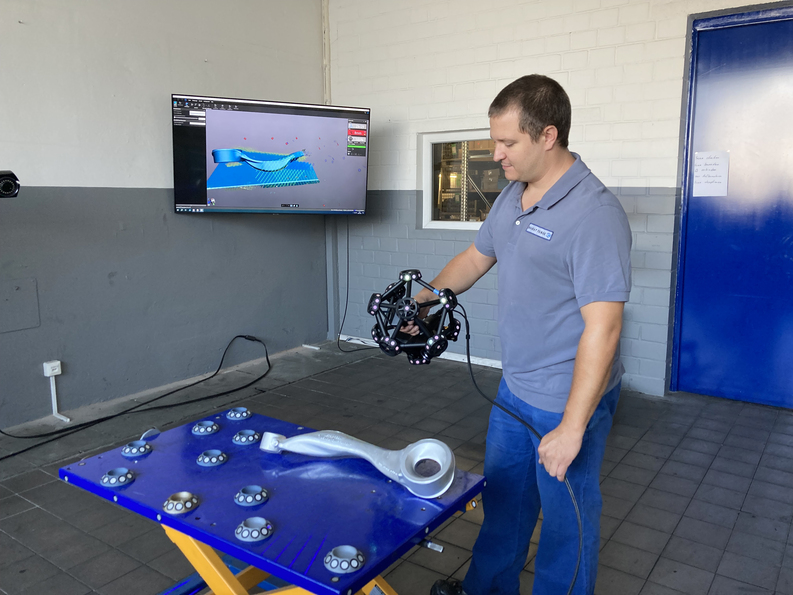Ingenieur in einer industriellen Umgebung, der den Creaform MetraSCAN 3D verwendet, um ein großes Teil in der Werkstatt zu scannen