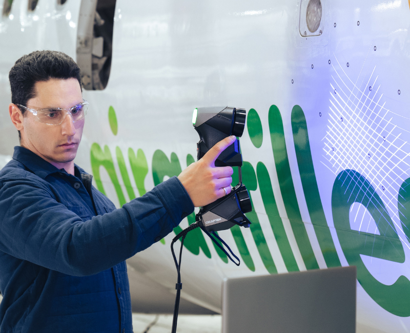 Man scanning the side of a plane with the HandySCAN 3D BLACK, whislt looking at the results on the laptop 