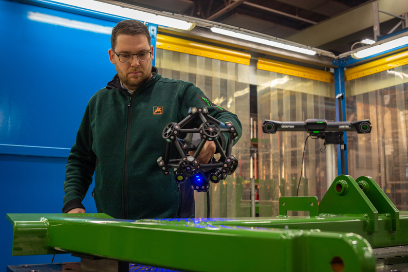 An engineer is using the Creaform MetraSCAN 3D to scan a large shiny part.